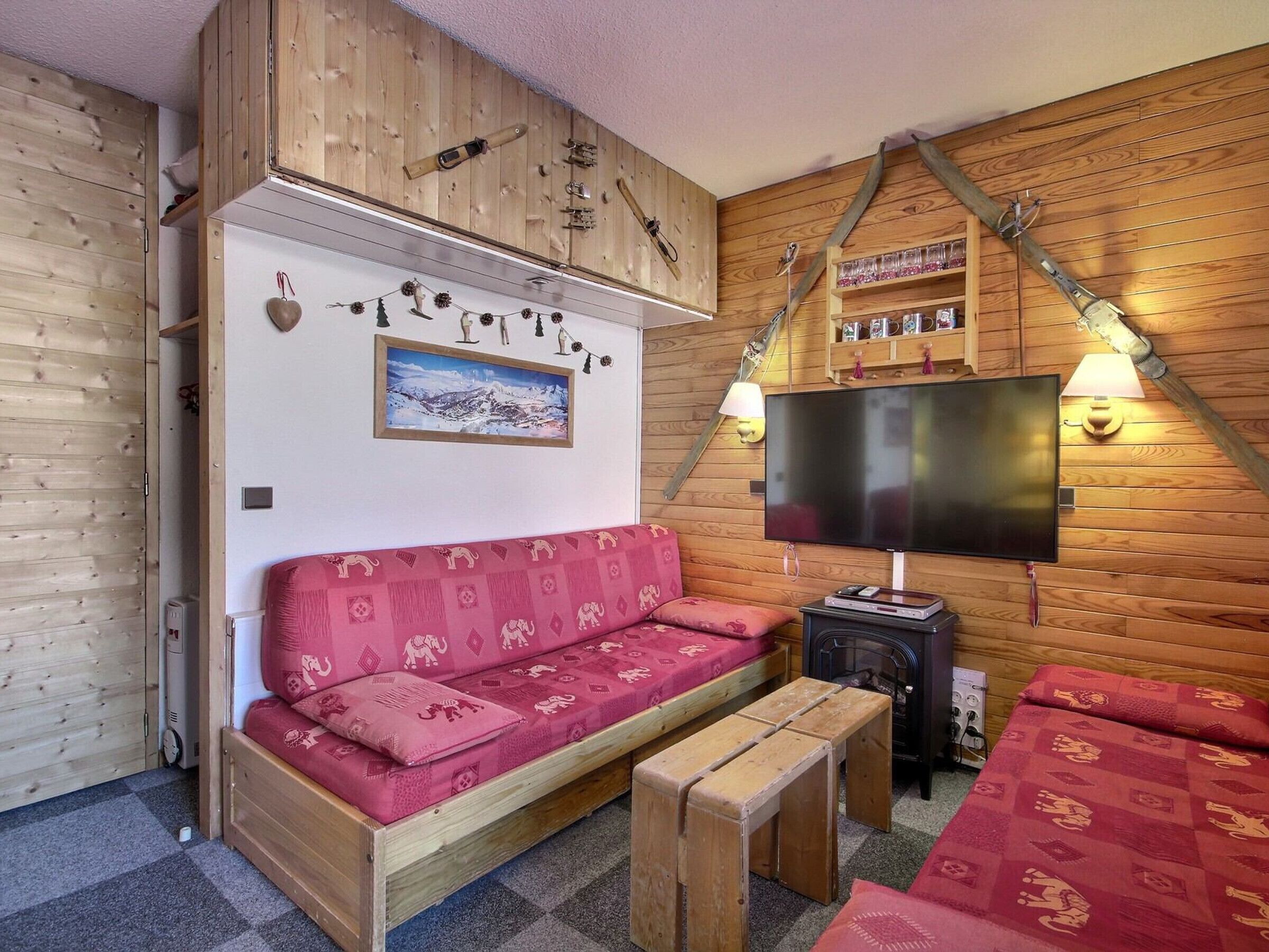 Une pièce chaleureuse avec un mur en bois, un canapé, une télévision et une cheminée.