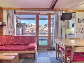 A cozy room with a sofa, a wooden table, and a television. - Central studio with balcony in Belle Plagne, 4 pers (Belle Plagne)