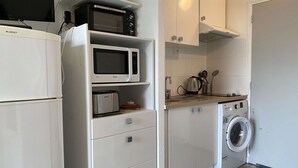 Una cocina compacta con microondas, tostadora y lavadora.