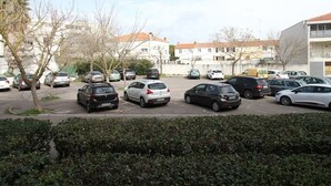 Un estacionamiento con varios coches y edificios al fondo.