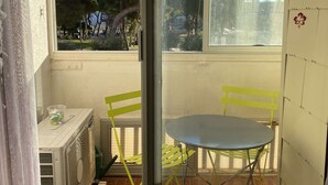Ein Balkon mit Tisch und Stühlen, ein Fenster mit Blick auf Bäume und eine Wand mit einem Kalender.
