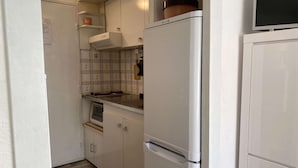 Eine kompakte Küche mit weißen Schränken, einem eingebauten Backofen und einem Kühlschrank.