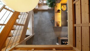 Un interior de madera con una escalera, un comedor con mesa y sillas, y una estantería mural para vinos.