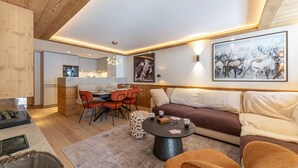 Ein modernes Wohnzimmer mit Holzboden, einem Essbereich mit roten Stühlen, einer Couch und einem Couchtisch.