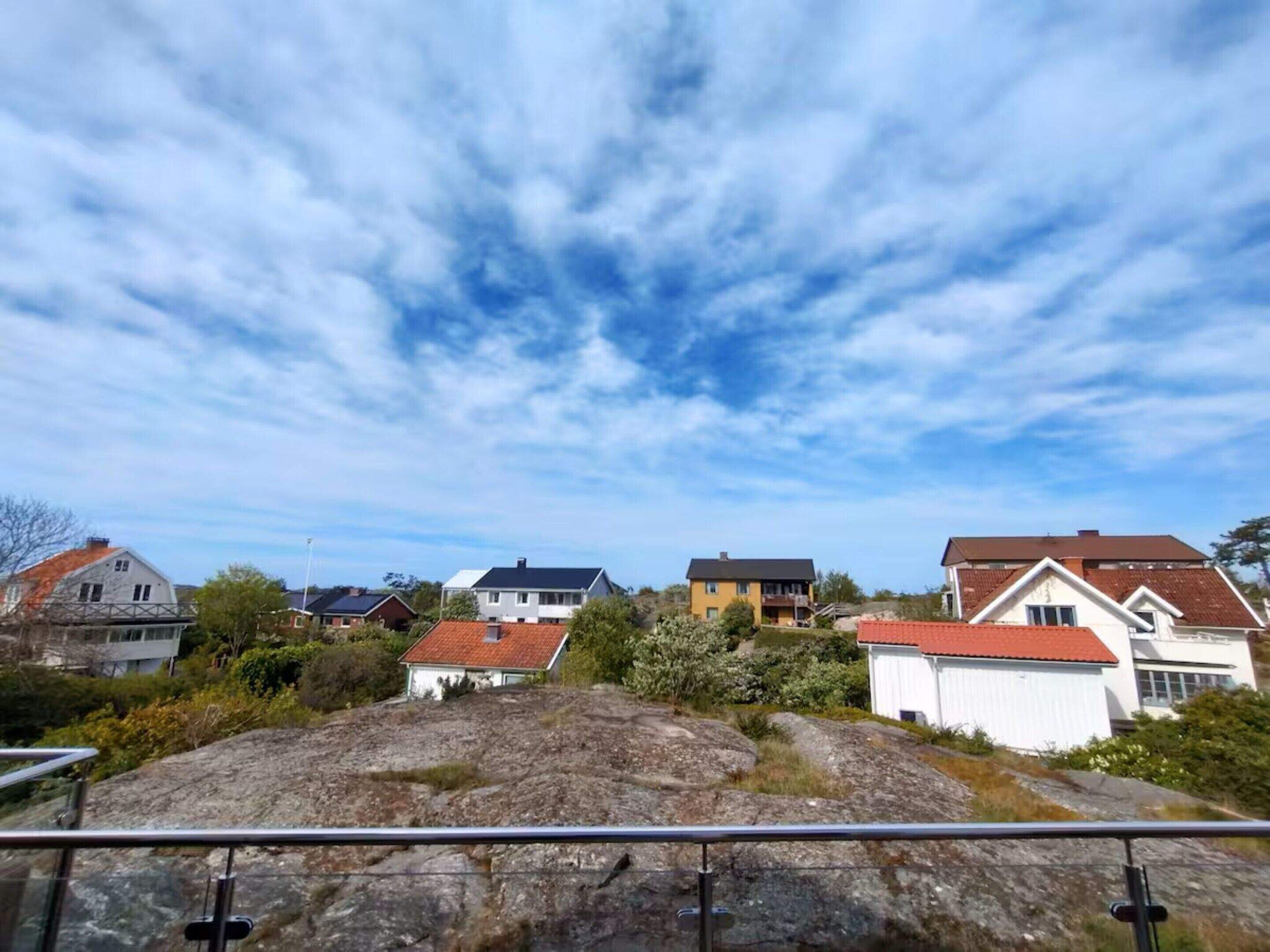 Ein Wohngebiet mit Häusern, felsigem Gelände im Vordergrund und wolkenlosem, blauem Himmel.