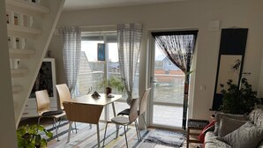 Una sala de estar moderna con comedor, una escalera y un ventanal con cortinas estampadas.