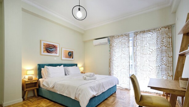 Een slaapkamer met een bed, nachtkastje, stoel en een tafel.