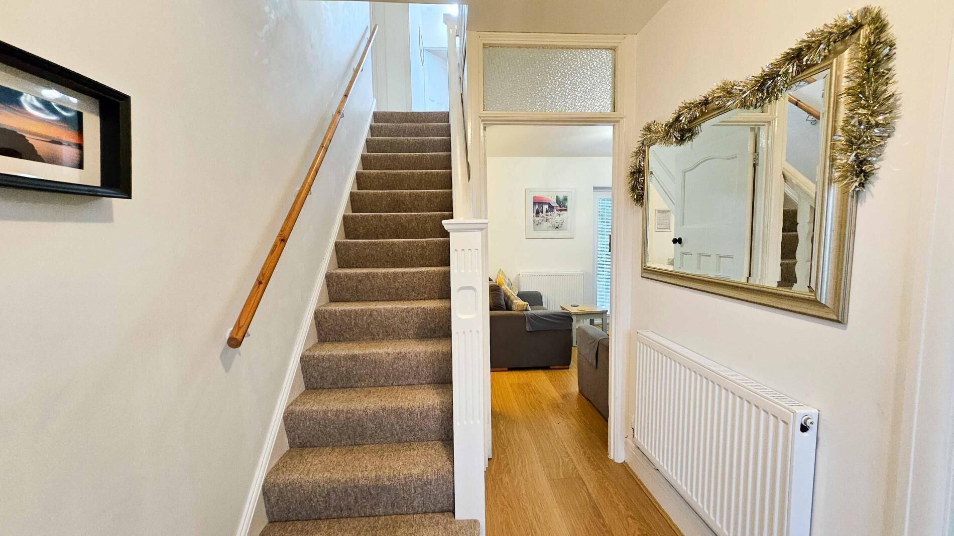 Una escalera con peldaños alfombrados que conduce a una sala de estar con un sofá y un cuadro en la pared.