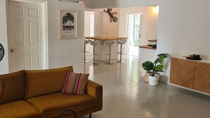 Een ruime woonkamer met een bank, een klein rond tafeltje en een plant in pot.