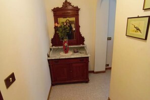 A hallway with a wooden cabinet, a mirror, and a framed picture on the wall. - Appartamento Olga - Comfort e posizione perfetta nel cuore della città (Camporosso)