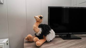 Ein Stofftier auf einer Holzfläche neben einem Fernseher.