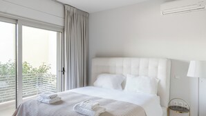 A modern hotel room with a large bed, a bedside table, and a view through the window. - New 2 Bedrooms, 2 Bath Apt in Central Glyfada, Fast WiFi, 10Min Walk to Beach (Glyfada)