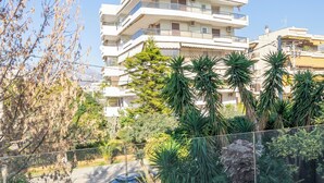 A multi-story residential building with balconies, surrounded by lush greenery and palm trees. - New 2 Bedrooms, 2 Bath Apt in Central Glyfada, Fast WiFi, 10Min Walk to Beach (Glyfada)