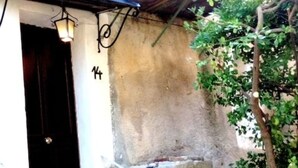 Une entrée d’immeuble avec une porte sombre, un mur blanc et le chiffre « 14 » peint sur le mur.