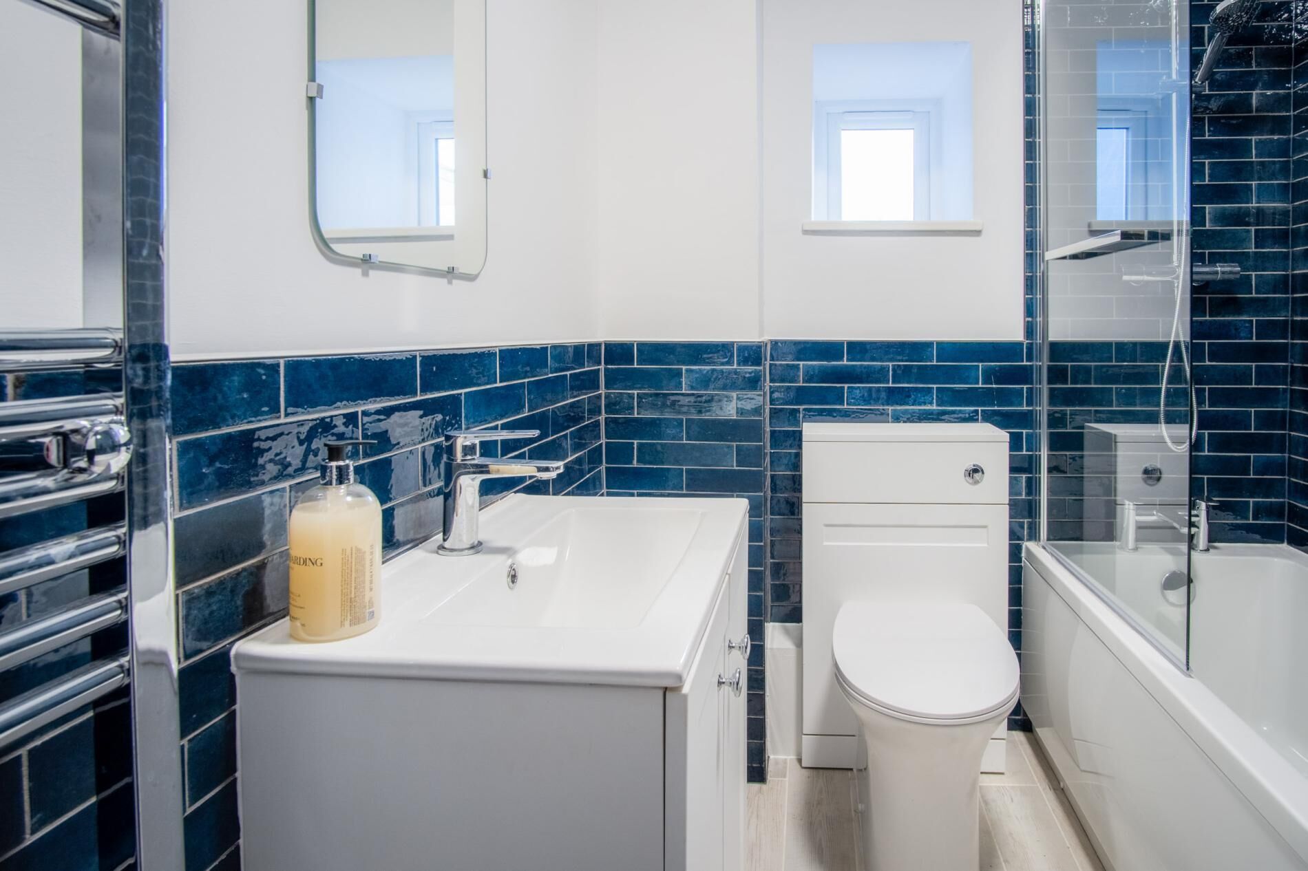 A modern bathroom with a white sink, a toilet, and a glass shower enclosure.