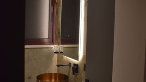 A bathroom with a copper sink, a mirror, and a door. - Stayinn Emerald (Shkodër)