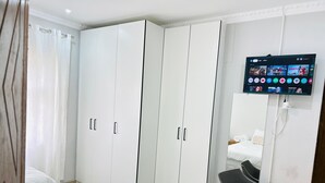 Ein Hotelzimmer mit einem Bett, einem Schreibtisch, einem Fernseher und einem Kleiderschrank.