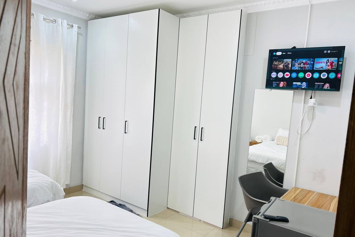 Une chambre d’hôtel équipée d’un lit, d’un bureau, d’une télévision et d’une armoire.
