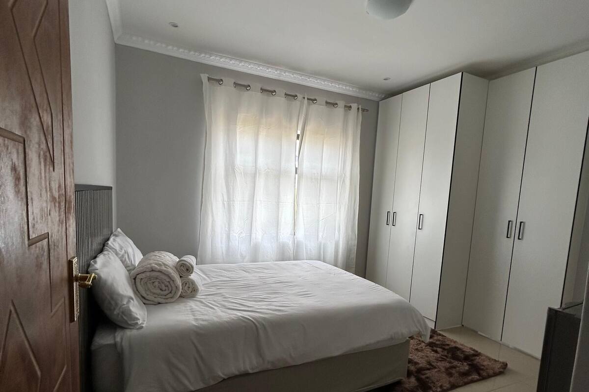 Une chambre à coucher avec un lit, une armoire, une porte et une fenêtre avec des rideaux.