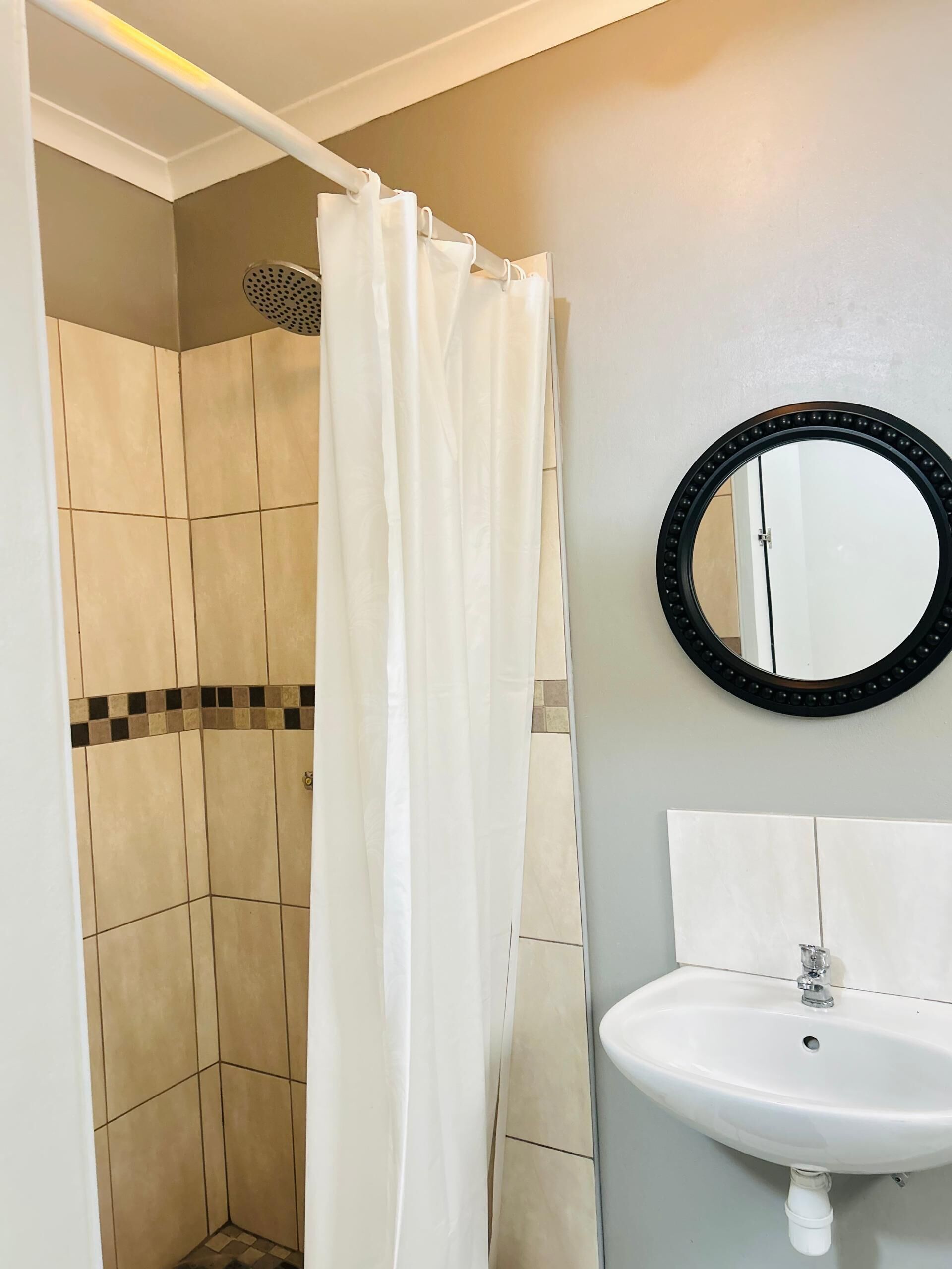 A bathroom with a shower, a sink, and a mirror.