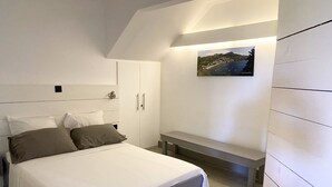 Un dormitorio con cama, un banco y un cuadro en la pared.