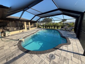 A swimming pool with a covered patio area, a hose, and lounge chairs. - 3-bedroom house in marvelous Port Charlotte with AC comfort and heated pool. (Port Charlotte)