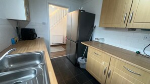 Eine kleine Küche mit Spüle, Kühlschrank und Holzschränken.