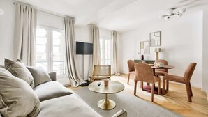 Een moderne woonkamer met een bank, een rond salontafeltje en een eethoek met stoelen.