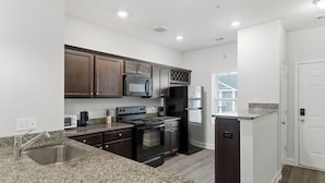 Una cocina moderna con encimeras de granito, electrodomésticos de acero inoxidable y armarios de madera oscura.