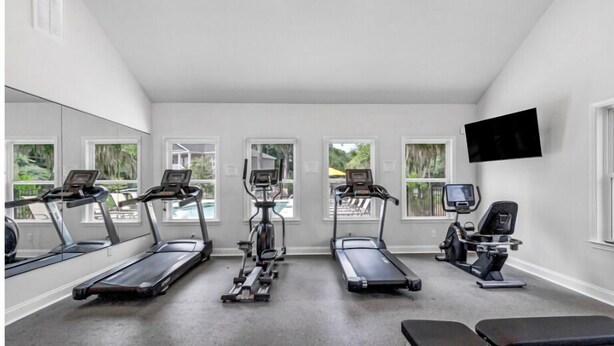 Une salle de sport à domicile équipée de quatre tapis de course, d’un vélo d’appartement et d’un téléviseur fixé au mur.