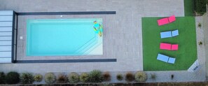 Luftaufnahme eines Schwimmbeckens mit Rettungsschwimmerstuhl und Pool-Schwimmer.