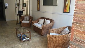 A lobby with wicker furniture, a glass coffee table, and artwork on the walls. - HOTEL AYRES (Colonia del Sacramento)