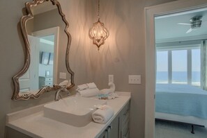 Une salle de bain avec un grand miroir, un lavabo et un porte-serviettes.