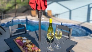 A poolside table with a bottle of white wine, two glasses, and a charcuterie board. - Ground Level Private Beach Home w/Pool & Beach Access- Adorable and affordable! (Gulf Shores)