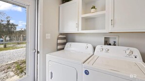 A laundry area with two washing machines, a cabinet above, and a door leading outside. - Ground Level Private Beach Home w/Pool & Beach Access- Adorable and affordable! (Gulf Shores)