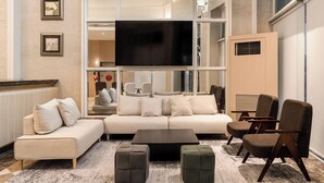A modern living room with a large flat-screen TV, a beige sofa, a coffee table, and two ottomans. - MUMU JIAO-XI (Jiaoxi)