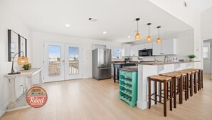 Una cocina moderna con armarios blancos, electrodomésticos de acero inoxidable y una isla central con taburetes de bar.
