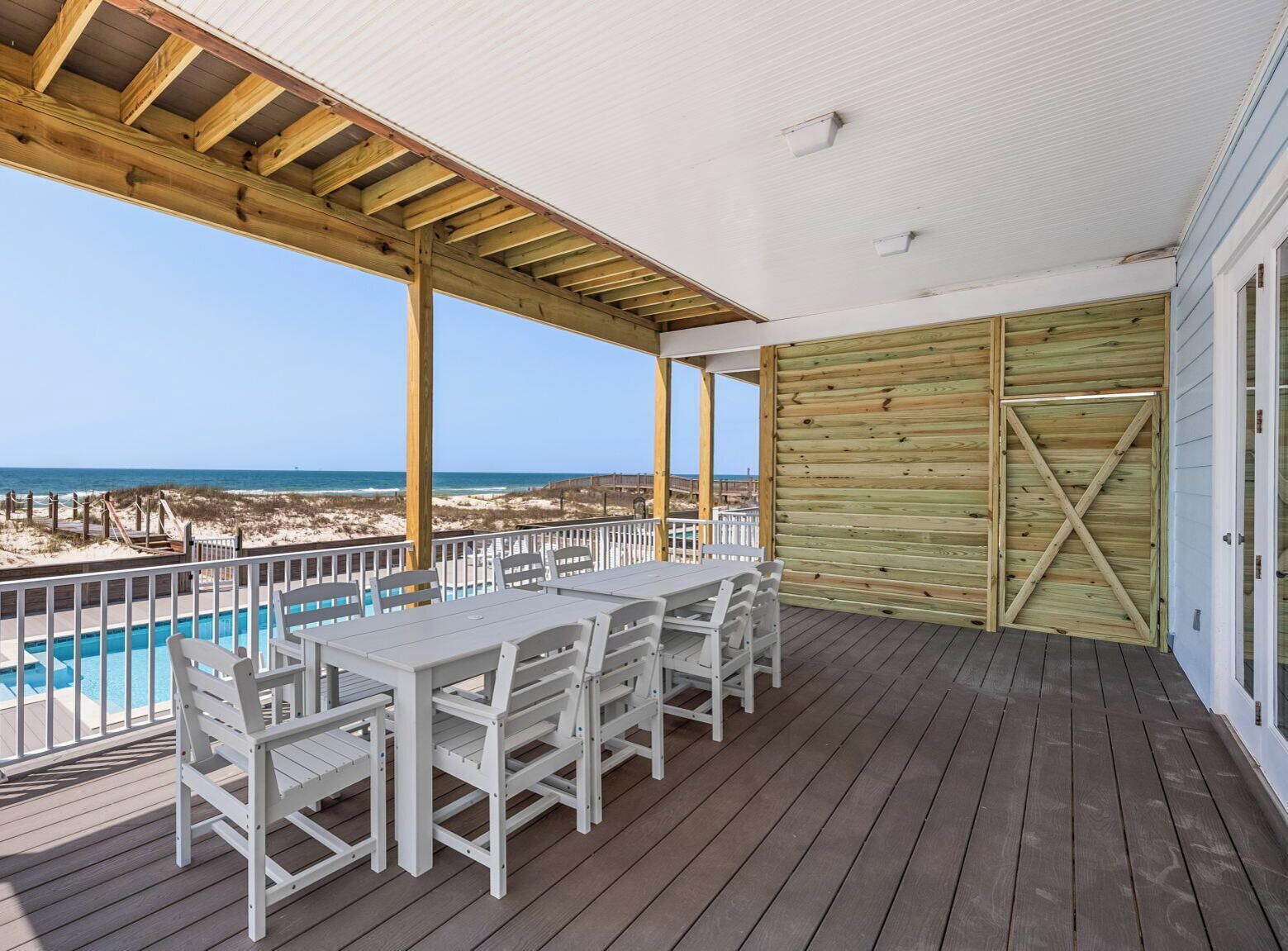 Un espace extérieur abrité comprenant une piscine, une terrasse en bois et une vue sur la plage.