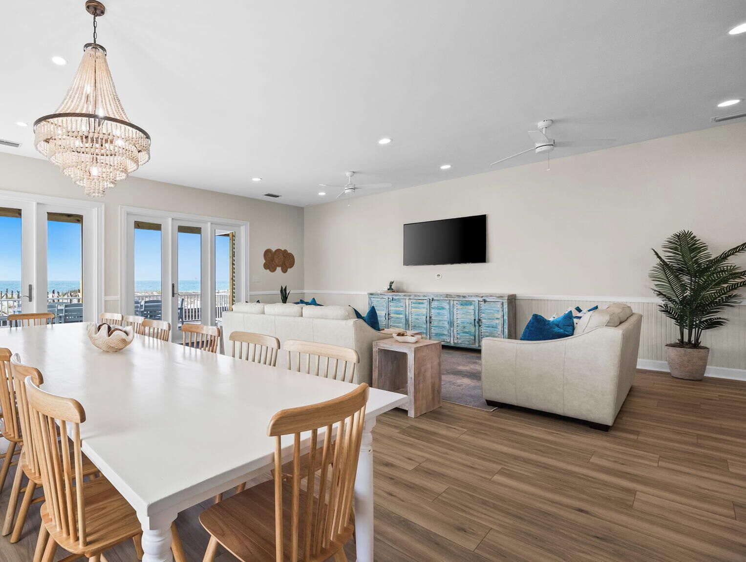 A spacious living area with a dining table, chairs, a sofa, a TV, and a ceiling fan.