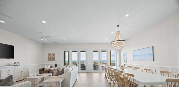A spacious living room with a large TV, seating area, and a view to the outside. - West Side Gorgeous 6 Br 4.5 Ba Beach Front Duplex - Newly Renovated! (Gulf Shores)