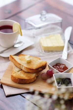 A breakfast setting with toast, jam, and a cup of tea on a wooden table.