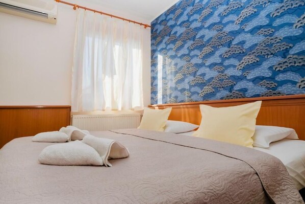 A hotel room with a bed, a window with curtains, a radiator, and a patterned wall. - König Hotel (Pécs)
