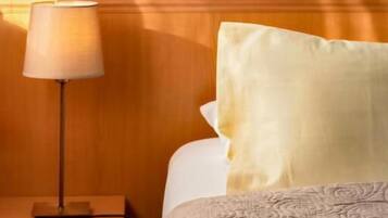 Ein Hotelzimmer mit einem hölzernen Kopfteil, einer Nachttischlampe, einem Nachttisch und einem Bett mit einem gemusterten Bettüberwurf.