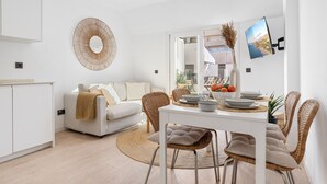 A modern, well-lit dining area with a white table, wicker chairs, and a view of the outdoors through a large window. - Fuengirola Center Rooftop Terrace (Fuengirola)