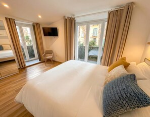 A hotel room with a large bed, a chair, a TV, and a balcony with curtains. - Conforti Suite - Modern apartment in the heart of the city (Salerno)
