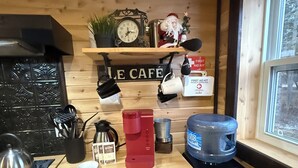 Eine Küche mit Holzwänden, einer Kaffeemaschine, einem Wasserspender und einer Erste-Hilfe-Ausrüstung auf einem Regal.
