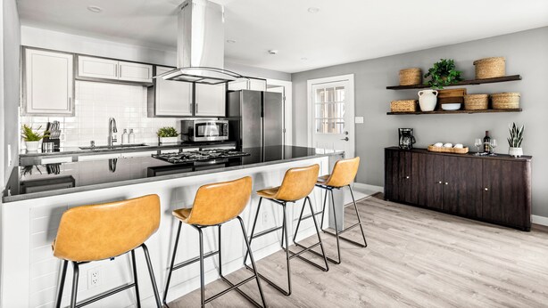 Une cuisine moderne dotée d’un îlot central, de tabourets de bar et d’un meuble en bois foncé agrémenté de paniers.