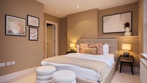 A bedroom with a large bed, bedside tables, and wall art. - Brick Lane Duplex Styled Living (London)
