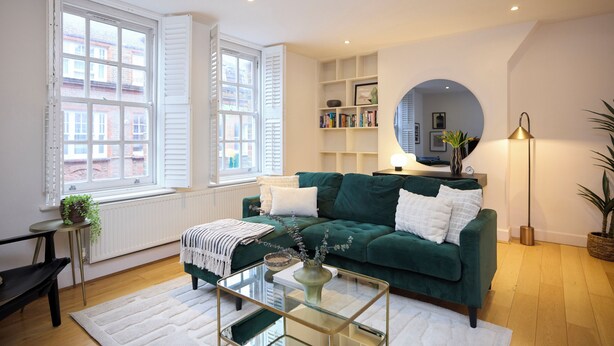 A living room with a green sofa, a coffee table, and a bookshelf. - Brick Lane Duplex Styled Living (London)