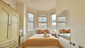 Un dormitorio con una cama grande, un armario, un espejo y ventanas con vista a la ciudad.